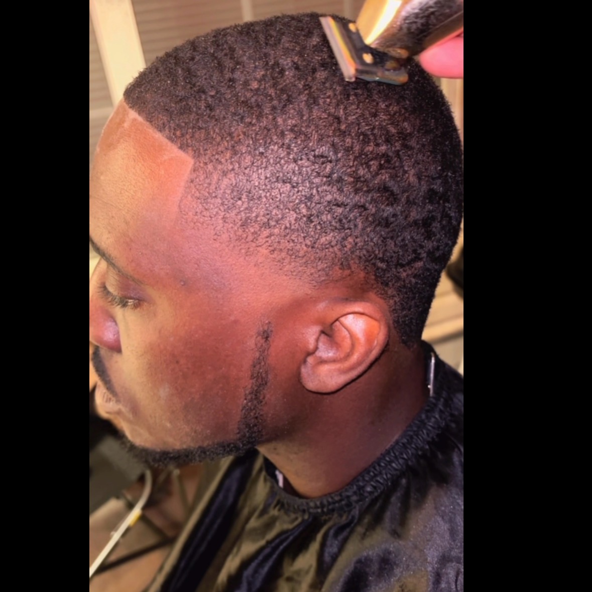 A barber working on a short haircut
